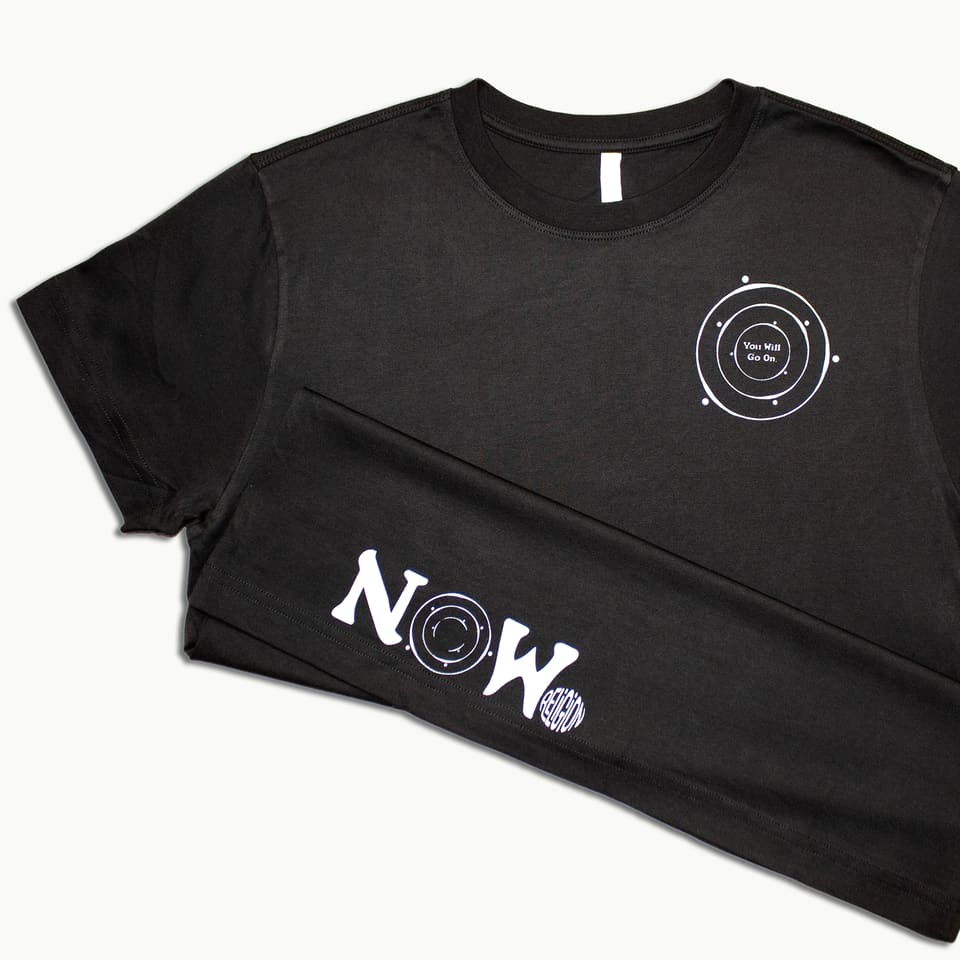Two black tees laid over each other showing a chest print and a 'NOW' hem print in white.
